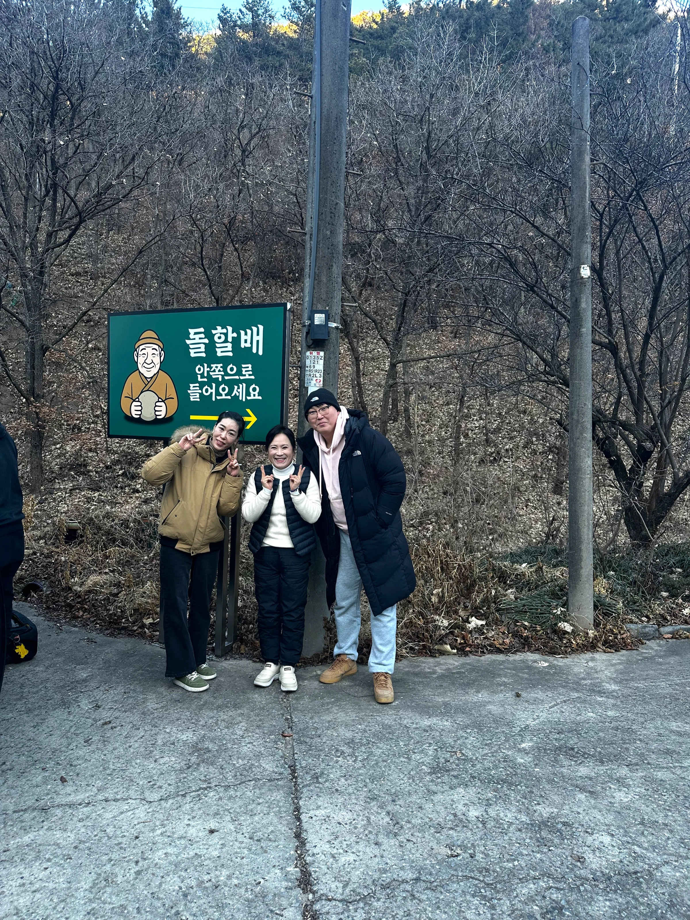 "돌할배 안쪽으로 들어오세요" 안내판 앞에서 가족 방문객들이 손가락 브이를 하며 웃고 있다.